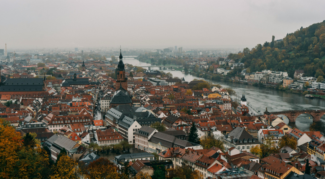 An illustrative photo of city buildings by a river.