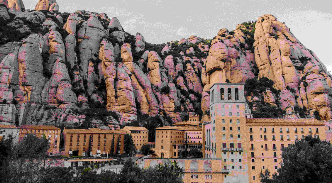 An illustrative photo of a large building with a large rock formation behind it.