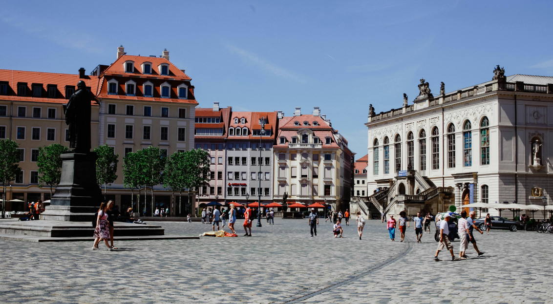 An illustrative photo of a group of people walking around a city square.