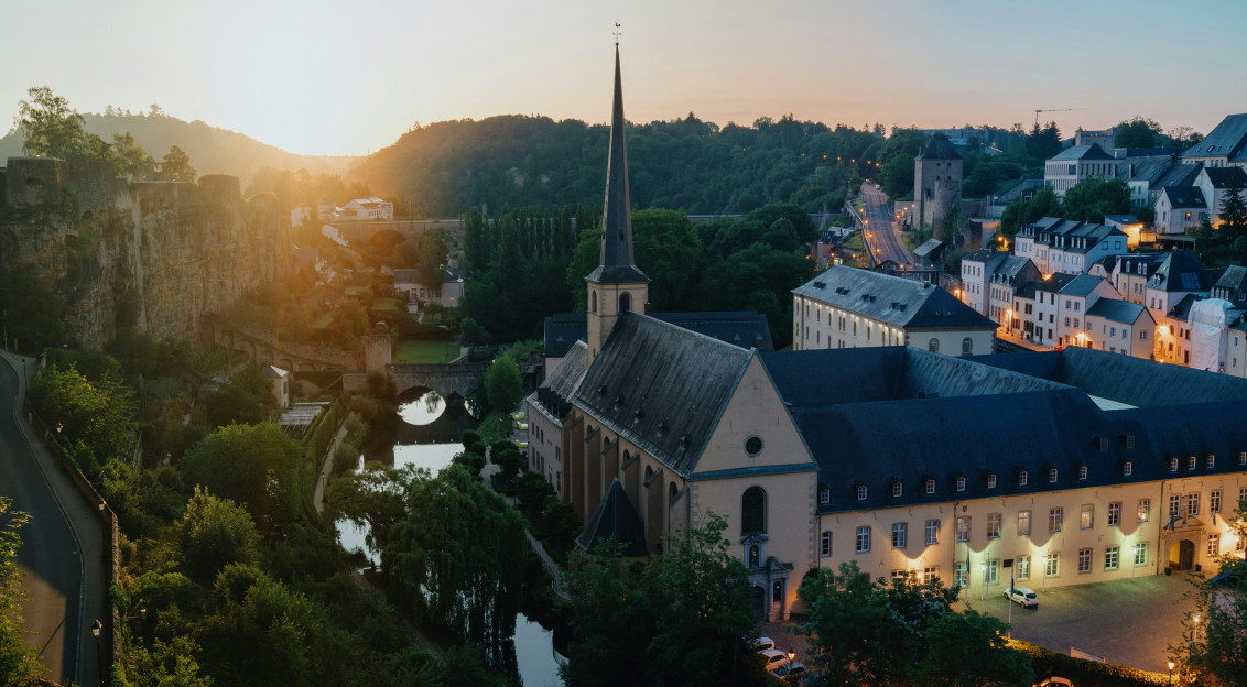 An illustrative photo of a castle in a city by a river.