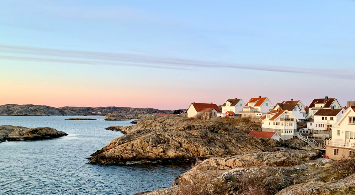 An illustrative photo of houses on a rocky coast near a body of water.