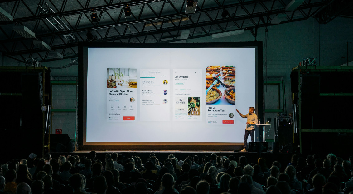 An illustrative photo of a person presenting to a big audience.