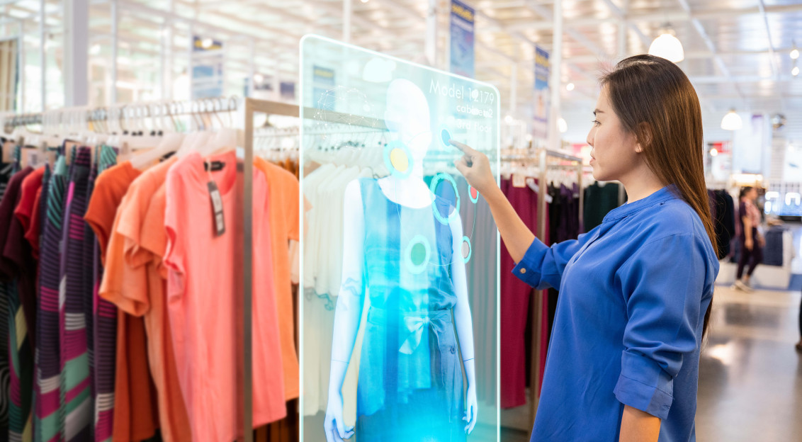 A photo presenting a shopper interacting with a digital display showing a virtual outfit in a clothing store.