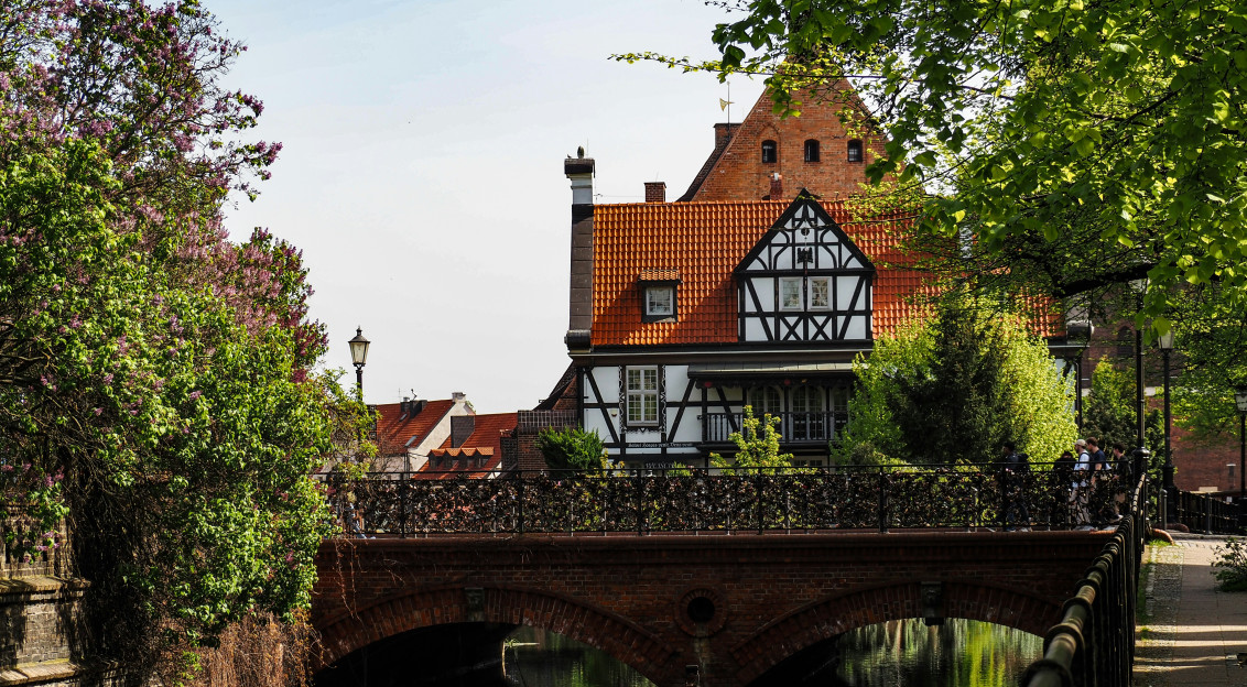 An illustrative photo of a bridge over a river with a house in the background.