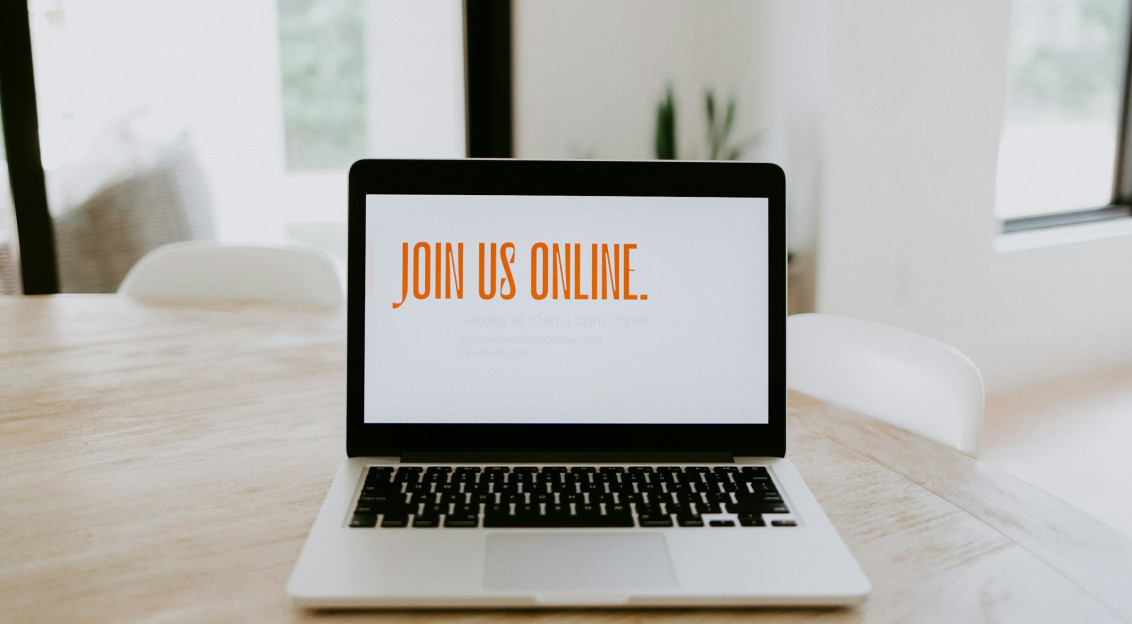 Laptop on a table displaying the message “Join us online,” suggesting a virtual event or online meeting invitation.