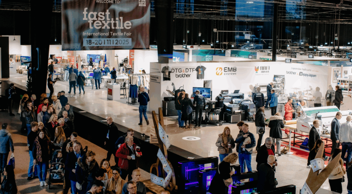 Wide view of a busy international textile trade fair with exhibition booths.