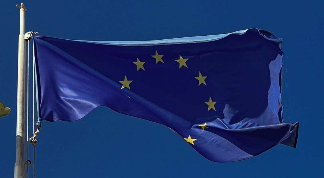 European Union flag flying in front of blue sky.
